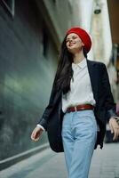 Fashion woman smile with teeth portrait walking tourist in stylish clothes in jacket with red lips walking down narrow city street flying hair, travel, cinematic color, retro vintage style. photo