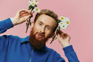 Portrait of a funny man smiling with a bouquet of flowers daisies on pink isolated background, copy place. Holiday concept and congratulations, Valentine's Day, Women's Day. photo