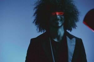 Fashion portrait of a man with curly hair on a blue background with a red stripe of light, multicolored light, trendy, modern concept. photo