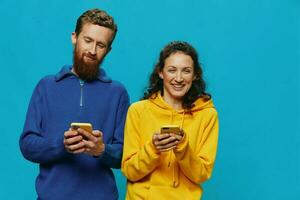 Woman and man cheerful couple with phones in their hands crooked smile cheerful, on blue background. The concept of real family relationships, talking on the phone, work online. photo