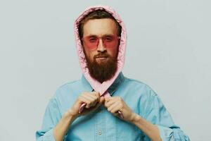 gracioso hombre en un rosado sombrero retrato en un ligero gris antecedentes. sonrisa y positivo emociones foto