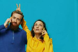 Woman and man cheerful couple with phones in their hands crooked smile cheerful, on blue background. The concept of real family relationships, talking on the phone, work online. photo