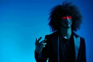 Fashion portrait of a man with curly hair on a blue background with a red stripe of light, multicolored light, trendy, modern concept. photo