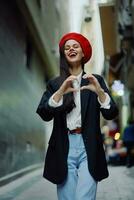 Moda mujer sonrisa con dientes retrato caminar turista con rojo labios caminando abajo estrecho ciudad calle firmar corazón de manos, amar, viajar, cinematográfico color, retro Clásico estilo, San Valentín día. foto