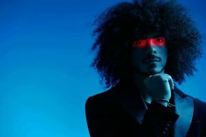 Fashion portrait of a man with curly hair on a blue background with a red stripe of light, multicolored light, trendy, modern concept. photo