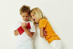 picture of positive boy and girl fun in colorful t-shirts with a notepad isolated background unaltered photo