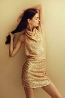 Beautiful woman in a gold sequined dress poses in a stylish look for a Christmas disco night party photo