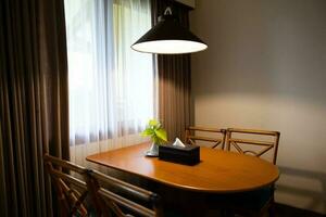 Dark home interior with wood dining table lit by lamp, evening light for dinner. photo