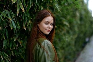 Portrait of happiness woman with red flying hair smile with teeth walking in the city in the park against a backdrop of green bamboo leaves, spring in the city photo