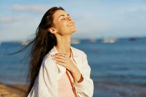 A woman with her eyes closed in the sun on a horse on the ocean smile, flying hair, tanned skin, rest, the concept of skin care in summer and spring. photo