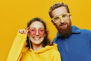 hombre y mujer Pareja sonriente alegremente y torcido con anteojos, en amarillo fondo, símbolos señales y mano gestos, familia disparar, recién casados. foto