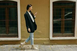 Woman blogger smile with teeth with a phone in her hands walks around the city fashion on the street, spring travel, vacation in the city tourist freelancer, mobile communication and internet for work photo