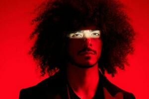 Fashion portrait of a man with curly hair on a red background, multinational, colored light, trendy, modern concept. photo