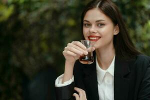 mujer sonrisa con dientes Bebiendo té en un café desde un turco vaso jarra en el calle foto