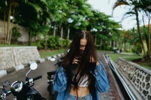 Portrait of a woman brunette smile with teeth walking outside against a backdrop of palm trees in the tropics, summer vacations and outdoor recreation, the carefree lifestyle of a freelance student. photo