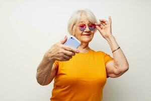 Portrait of an old friendly woman in a yellow t-shirt posing communication by phone cropped view photo