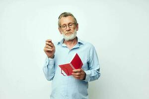 Senior grey-haired man writes down emotions in a notebook light background photo