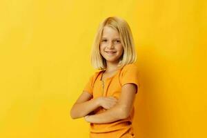 linda pequeño niña en un amarillo camiseta sonrisa posando estudio color antecedentes inalterado foto