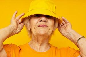 Portrait of an old friendly woman in casual t-shirt yellow panama cropped view photo