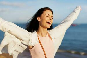 Woman smile with teeth freedom on vacation walking on the beach by the ocean in Bali sunset, happy travel and relaxation, sunset light, flying hair, the concept of change and emotional health photo