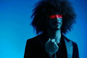 Fashion portrait of a man with curly hair on a blue background with a red stripe of light, multicolored light, trendy, modern concept. photo