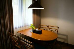 Dark home interior with wood dining table lit by lamp, evening light for dinner. photo