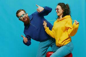 Woman and man smile sitting on suitcase with red suitcase smile, on blue background, packing for trip, family vacation trip. photo