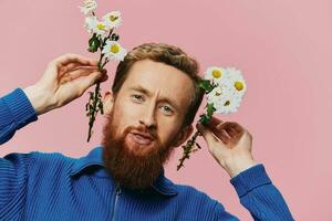 Portrait of a funny man smiling with a bouquet of flowers daisies on pink isolated background, copy place. Holiday concept and congratulations, Valentine's Day, Women's Day. photo