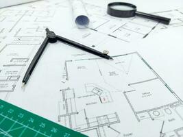 Architect rolls, compass, magnifier glass and house plans, close up. Side view photo