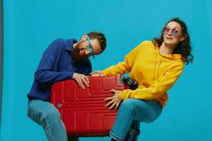 mujer y hombre sonrisa maletas en mano con amarillo y rojo maleta sonrisa divertido, en azul fondo, embalaje para un viaje, familia vacaciones viaje. foto