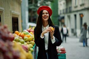 mujer sonrisa con dientes turista camina en el ciudad mercado con frutas y vegetales escoger bienes, elegante de moda ropa y constituir, primavera caminar, viajar. foto