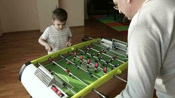 Father and a son are playing table football game video