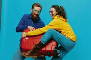 mujer y hombre sonrisa maletas en mano con amarillo y rojo maleta sonrisa divertido, en azul fondo, embalaje para un viaje, familia vacaciones viaje. foto