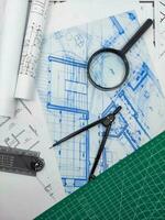 Architect engineer office desk. Blueprint plans and house model with ruler, compass, and magnifier glass photo