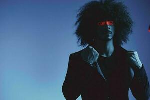 Fashion portrait of a man with curly hair on a blue background with a red stripe of light, multicolored light, trendy, modern concept. photo