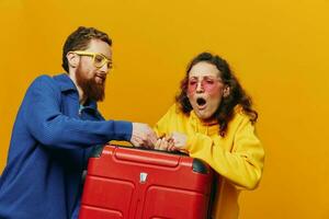 Woman and man smiling, suitcases in hand with yellow and red suitcase smiling merrily and crooked, yellow background, going on a trip, family vacation trip, newlyweds. photo