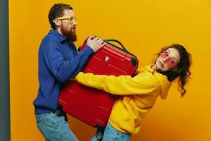 mujer y hombre sonriente, maletas en mano con amarillo y rojo maleta sonriente alegremente y torcido, amarillo fondo, yendo en un viaje, familia vacaciones viaje, recién casados. foto