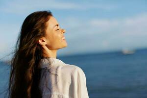 Woman beauty smile with teeth freedom on vacation walking on the beach by the ocean in Bali sunset, happy travel and vacation, sunset light, flying hair, skin and hair care concept in the sun photo