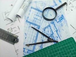 Architect engineer office desk. Blueprint plans and house model with ruler, compass, and magnifier glass photo