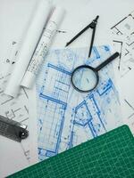 Architect engineer office desk. Blueprint plans and house model with ruler, compass, and magnifier glass photo