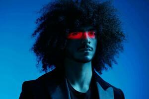 Fashion portrait of a man with curly hair on a blue background with a red stripe of light, multicolored light, trendy, modern concept. photo