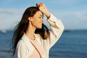 Woman beauty smile with teeth freedom on vacation walking on the beach by the ocean in Bali sunset, happy travel and vacation, sunset light, flying hair, skin and hair care concept in the sun photo