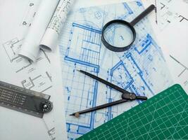 Architect engineer office desk. Blueprint plans and house model with ruler, compass, and magnifier glass photo