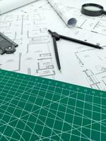 Architect rolls, compass, magnifier glass and house plans, close up. Side view photo