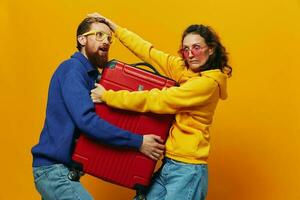 Woman and man smiling, suitcases in hand with yellow and red suitcase smiling merrily and crooked, yellow background, going on a trip, family vacation trip, newlyweds. photo