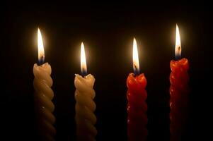 burning candle flame or light glowing on four spiral candles on black or dark background on table in church for Christmas, funeral or memorial service with copy space. photo