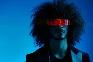 Fashion portrait of a man with curly hair on a blue background wearing red sunglasses, multinational, colored light, trendy, modern concept. photo