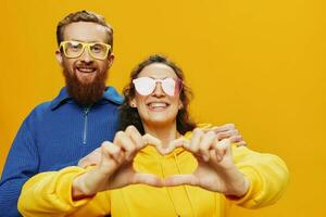 Man and woman couple smiling cheerfully and crooked with glasses, on yellow background, symbols signs and hand gestures, family shoot, newlyweds. photo