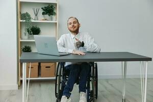 Man in wheelchair businessman in office at laptop, smile and happiness, thumbs up, concept of work disabled person, freedom from social frames photo