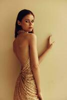 Young slender woman in gold sequined dress with open back, disco party style Christmas look photo